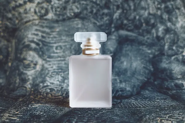 Frasco de perfume fosco sem marca sobre fundo de pedra esculpida