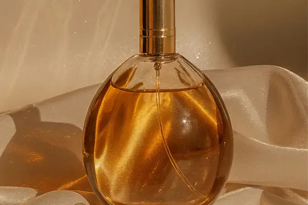 Frasco de perfume dourado sem marca sobre tecido acetinado
