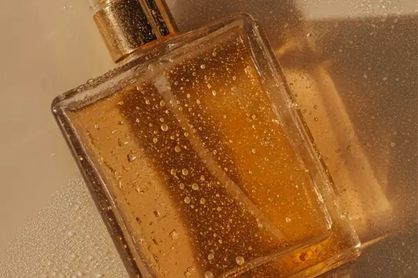 Detalhe de frasco de perfume âmbar com gotas de água