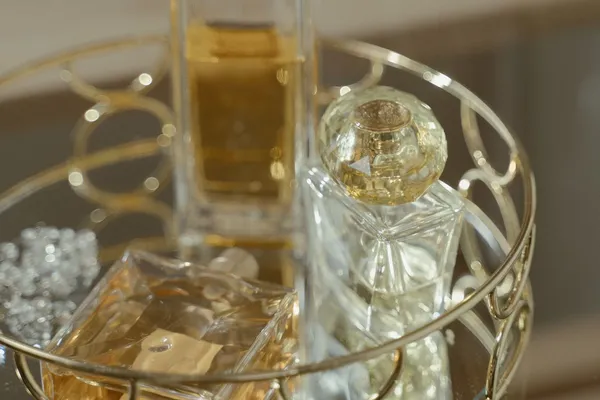 Frascos de perfume de vidro sem marca sobre bandeja dourada espelhada